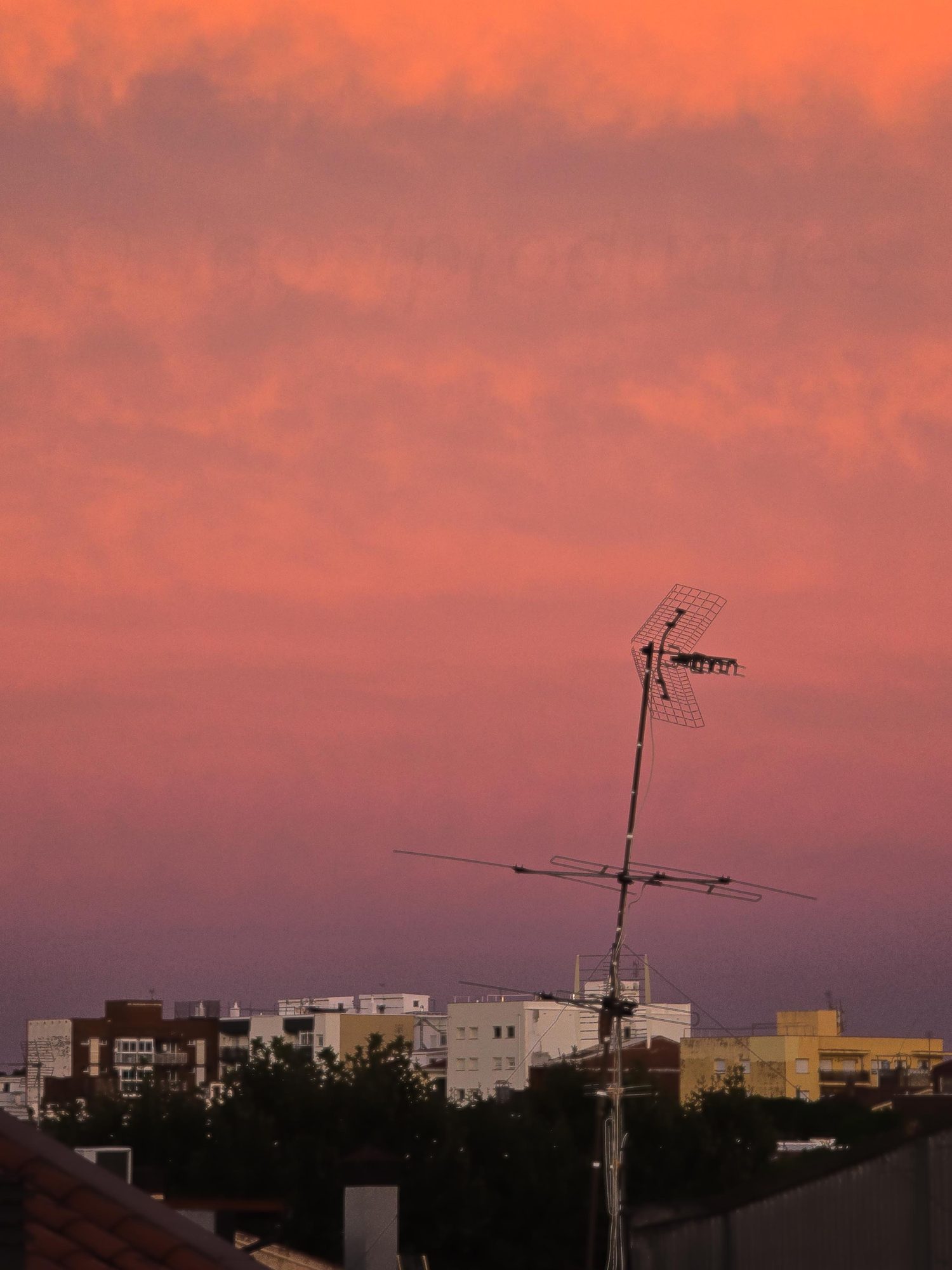 Antenne op een dak tegen een roze avondlucht